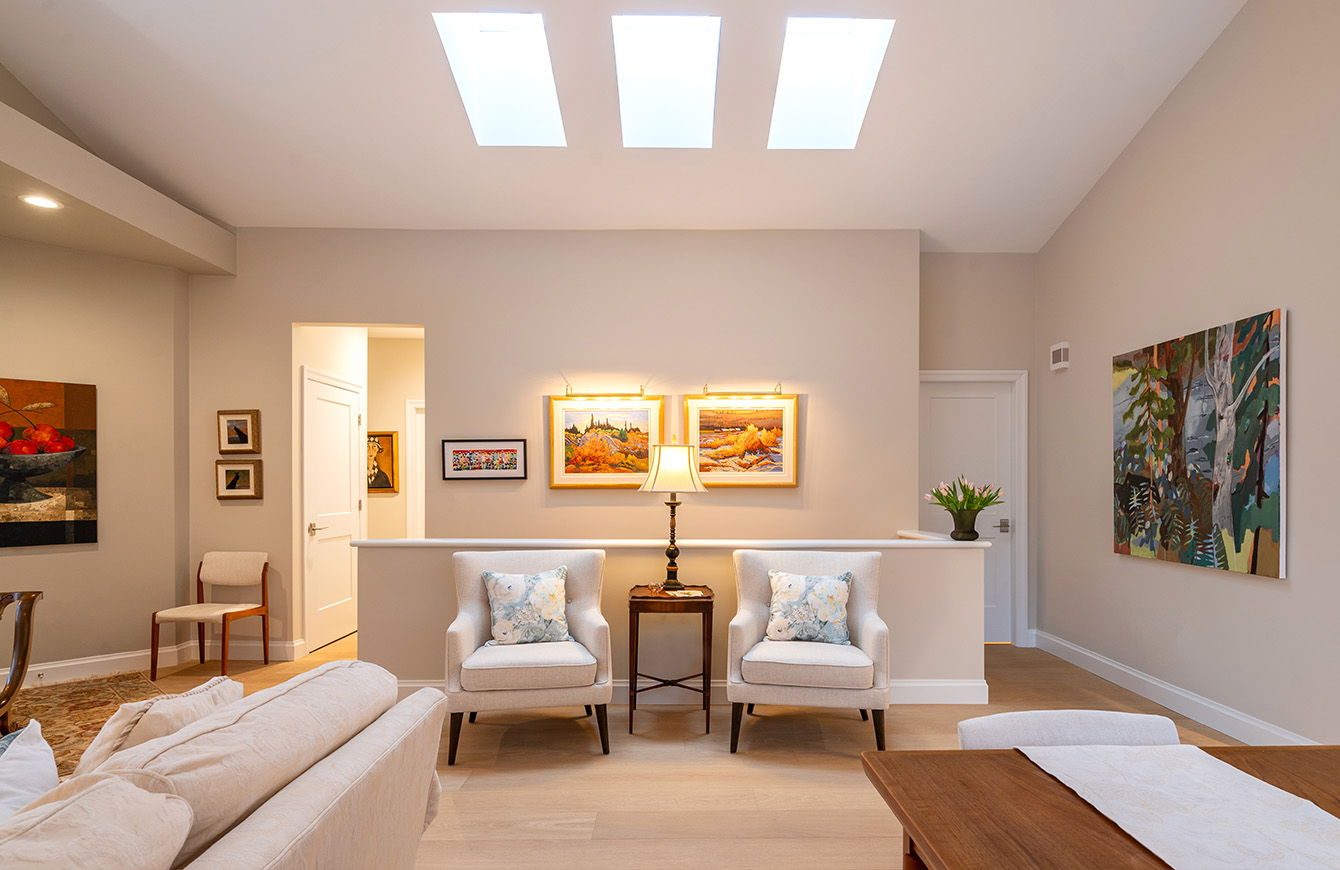 Modern living room featuring table, chairs, and skylight for bright ambiance.