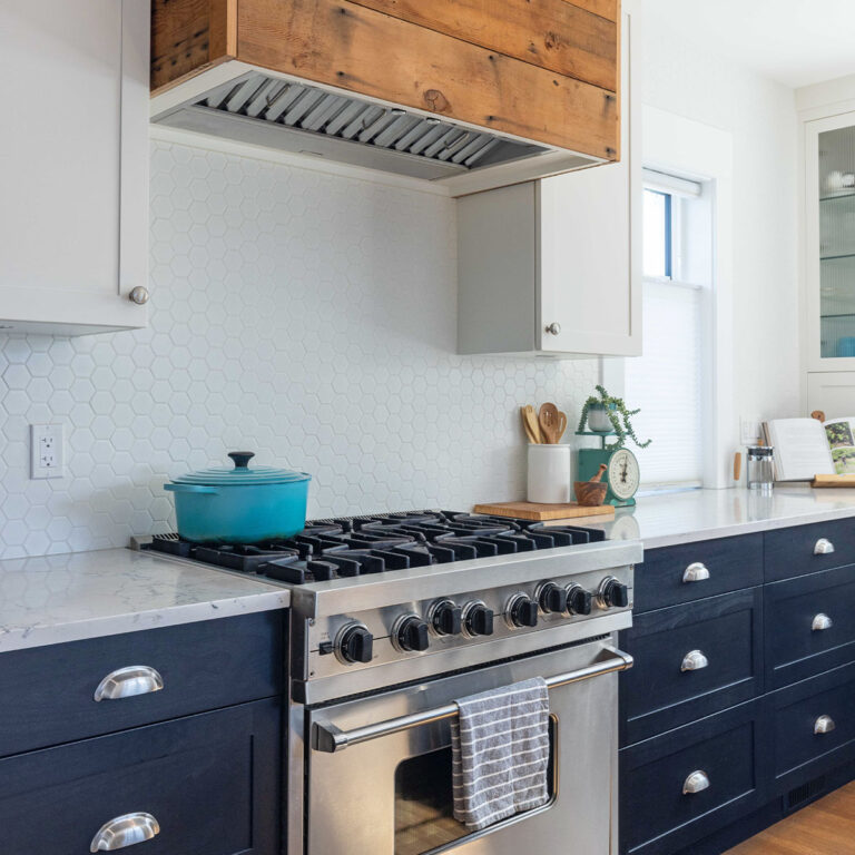 Spaces15-home-renovation-vancouver-2 A kitchen with black cabinets and white counter tops, creating a fresh and modern look.