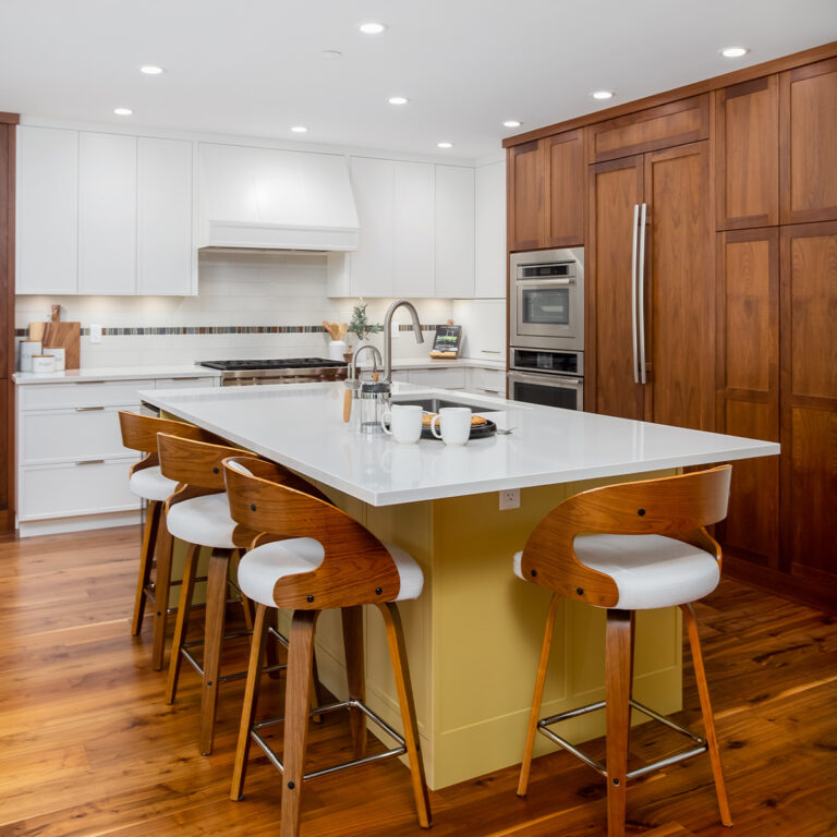 Spaces17-home-renovation-maple- ridge-3 A kitchen with a white island and wooden cabinets.