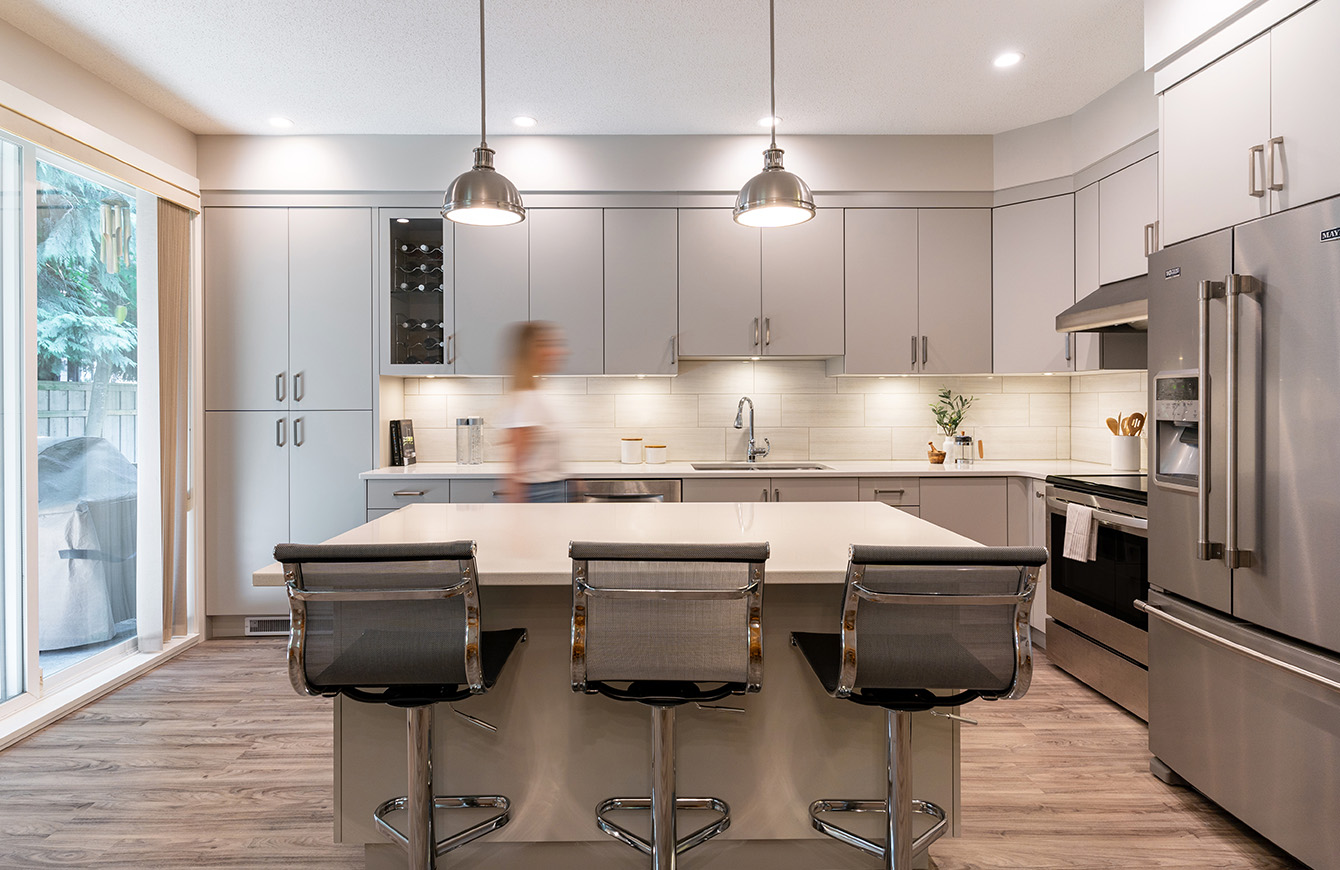 A modern kitchen with a sleek white island and shiny stainless steel appliances.