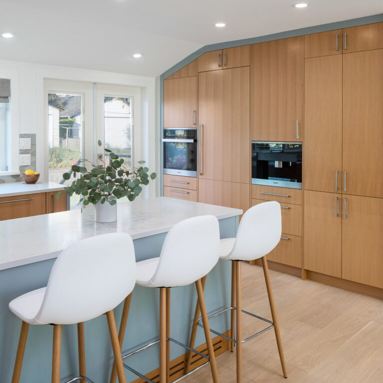 Spaces21-home-renovation-burnaby-2 Kitchen with blue and white countertops and stools, creating a fresh and modern look.