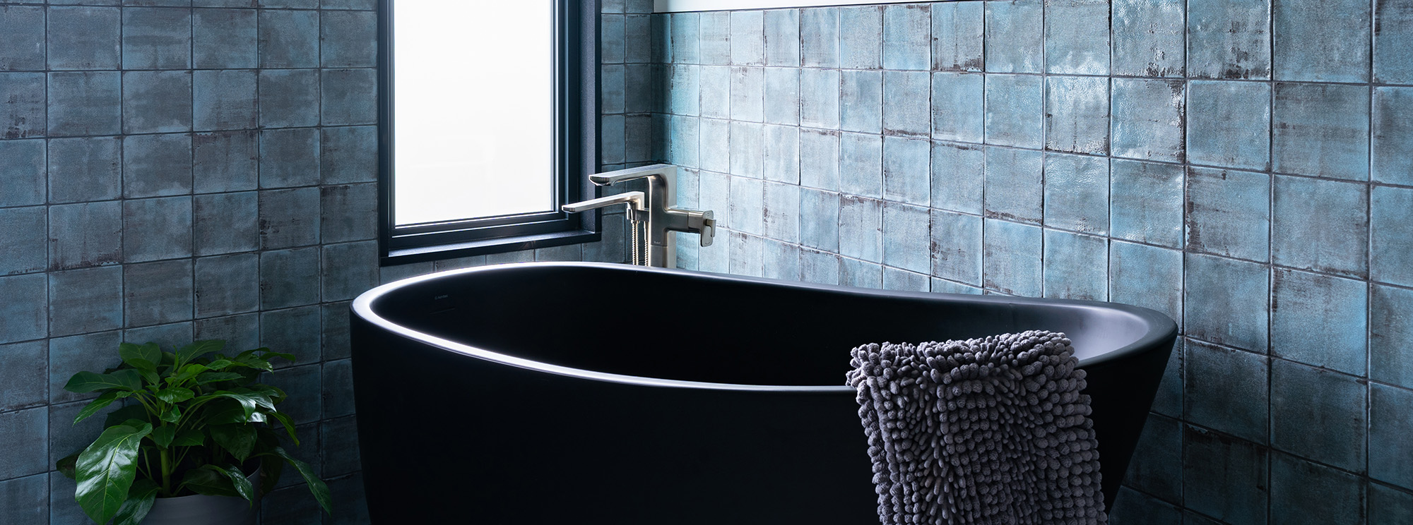 A sleek black bathtub in a bathroom with cool blue tiles. A perfect blend of elegance and tranquility.