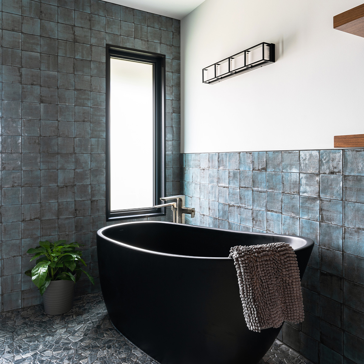 A sleek bathroom with a black bathtub and a window, offering a perfect blend of style and natural light.