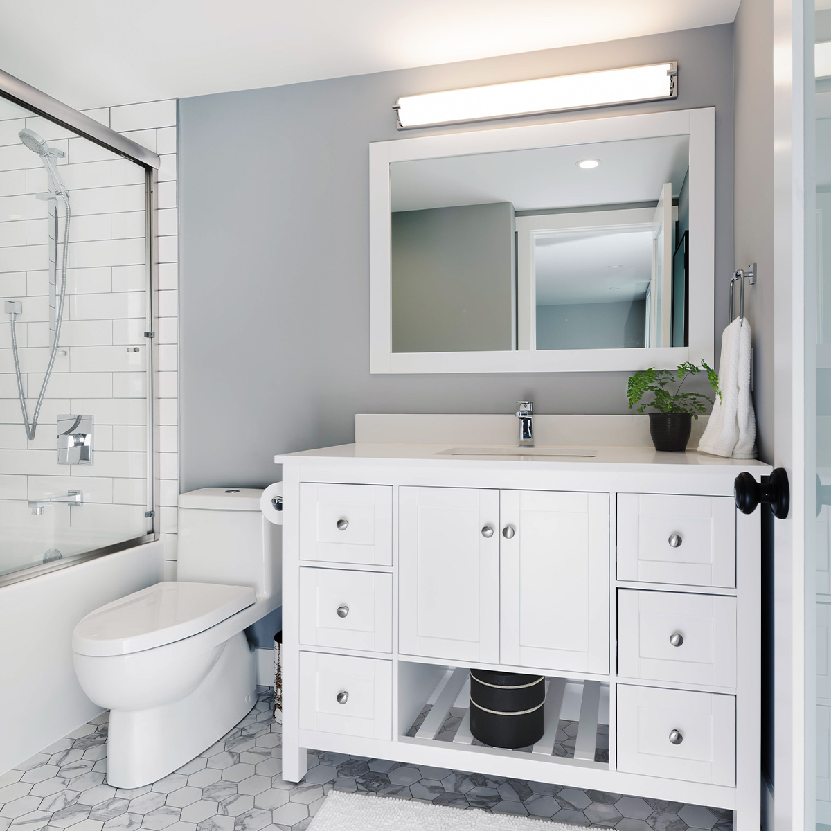 A clean bathroom with a white sink, toilet, and shower.